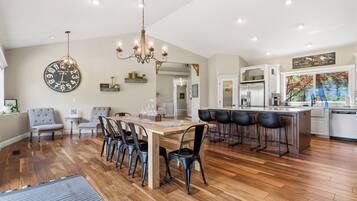 A spacious kitchen with a dining area, wooden flooring, and modern appliances.
