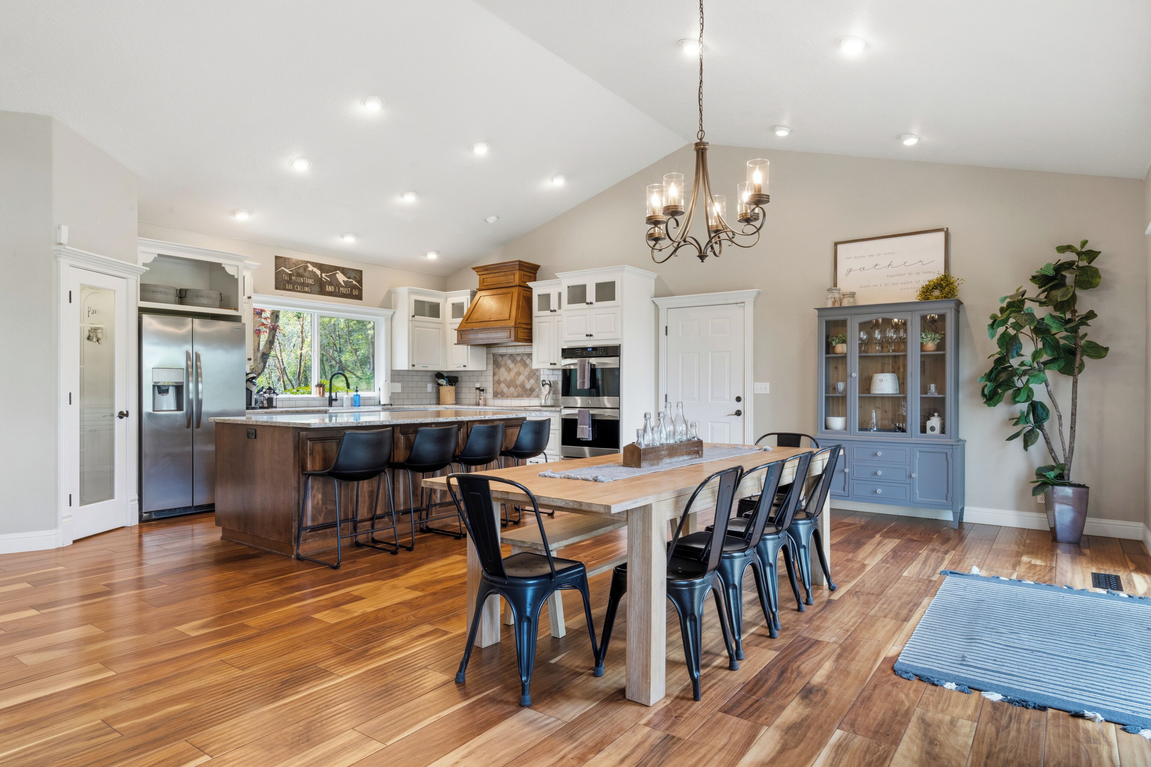 A spacious kitchen with a central island, bar stools, and a dining table.