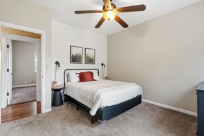 A bedroom with a bed, a ceiling fan, a nightstand, a wall-mounted lamp, and two framed pictures. - Luxury mountain-top retreat with private pool, hot tub, breathtaking views, and total privacy. Sleeps 17 with spacious living areas, gourmet kitchen, and kid-friendly game space. Minutes to Jacksonville, wineries, and Ashland. (Jacksonville)