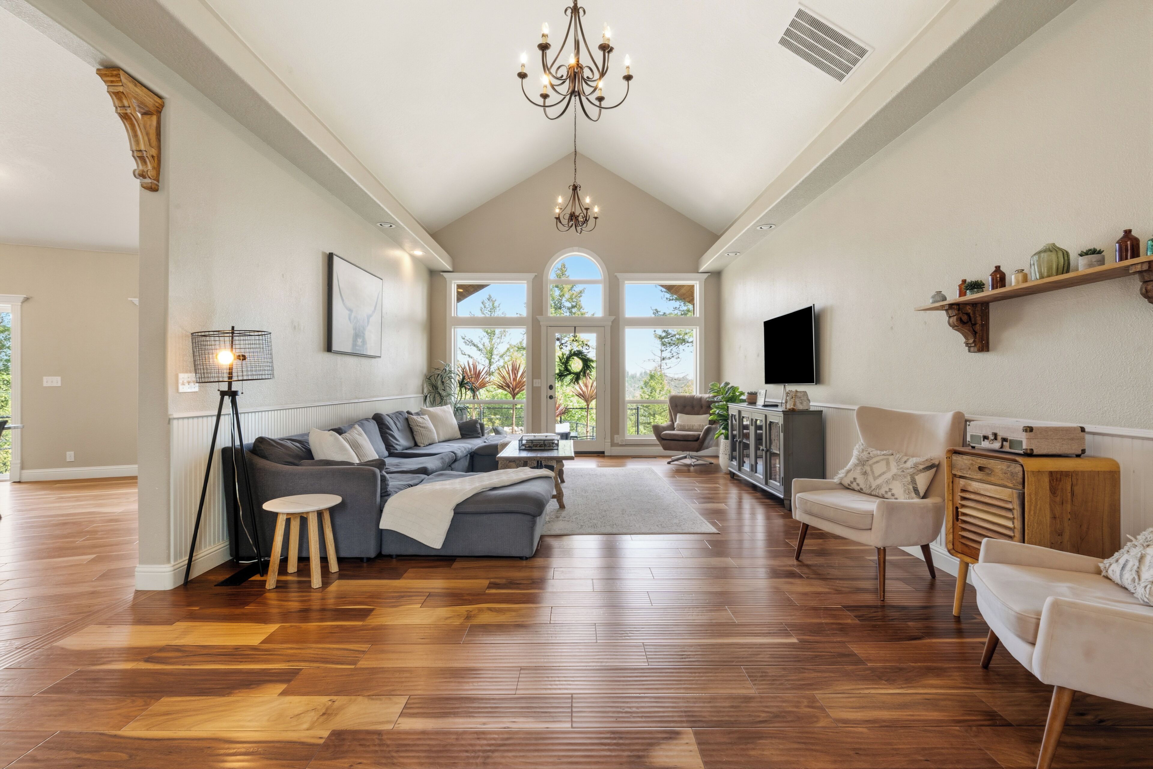 A spacious living room with a large sectional sofa, a television, and a chandelier.