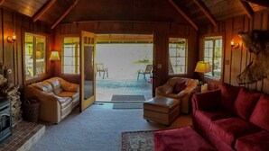 A cozy room with a fireplace, leather sofas, and a red armchair. - HISTORIC RUSHING WATER LODGE on the rogue river was built in 1910 (Eagle Point)