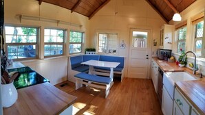 A compact kitchen with a wooden countertop, a sink, a stove, and a seating area with blue cushions. - HISTORIC RUSHING WATER LODGE on the rogue river was built in 1910 (Eagle Point)