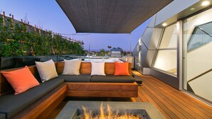 Un espace extérieur aménagé avec un foyer, une terrasse en bois et une vue sur les gratte-ciel de la ville.