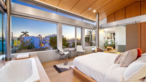 Une chambre moderne avec un grand lit, une baignoire et une vue sur la ville.