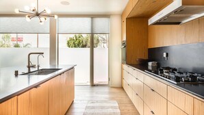Une cuisine moderne dotée d’un grand îlot central, de meubles en bois et d’une cuisinière noire.