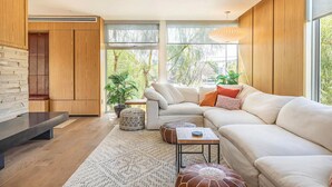 Un salon moderne avec un canapé d’angle, une table basse et une plante en pot.
