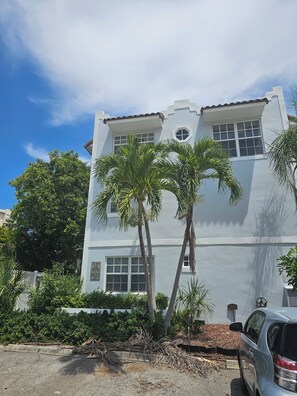 A two-story building with a white exterior, multiple windows, and a car parked in front. - Beautiful  Townhouse, a few steps from the Beach (Lauderdale-By-The-Sea)