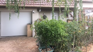 Ein Haus mit Ziegeldach, Garagentor und hängenden Pflanzen.