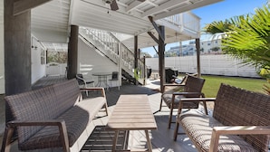 A covered outdoor patio with wicker furniture, a table, and a ceiling fan. - Updated Blue Mountain Beach Condo! (Santa Rosa Beach)