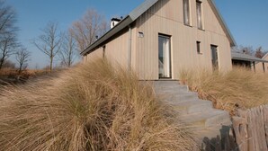 A modern house with a sloped roof, a visible number '157', and a set of concrete steps leading to the front door. - Oesterdam Resort by Interhome (Tholen)
