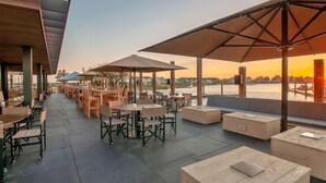 An outdoor seating area with tables and chairs, umbrellas, and a view of the water. - Oesterdam Resort by Interhome (Tholen)