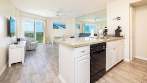 A modern kitchen with a dishwasher, a coffee maker, and a dining area with a table and chairs.