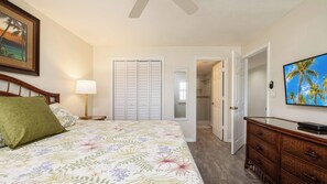 A bedroom with a bed, a nightstand, a lamp, a dresser, a TV, a closet, and a bathroom door. - Perfect Location+Beautiful Ocean Views+Pool & Bar (Tavernier)