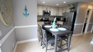 A modern kitchen with white cabinets, a stainless steel refrigerator, a microwave, and a stove.
