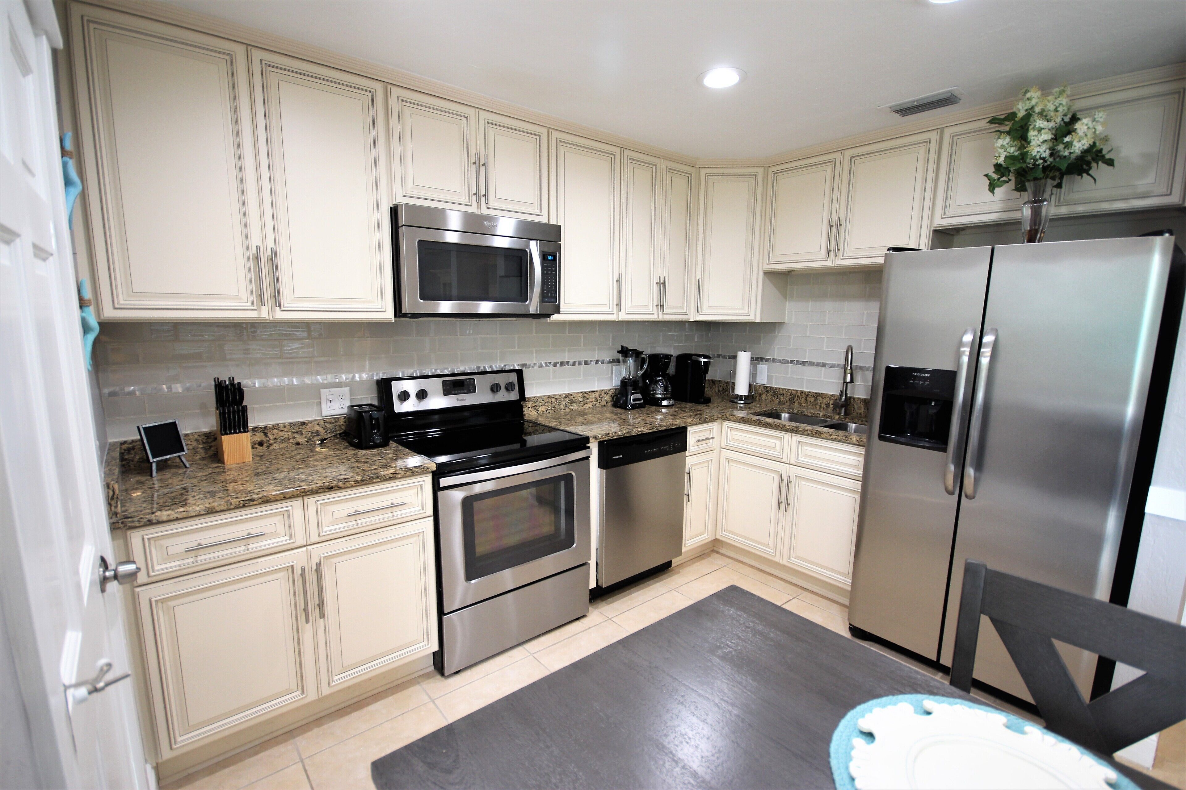 A modern kitchen with white cabinets, stainless steel appliances, and a granite countertop.
