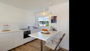 Una cucina moderna con mobili bianchi, forno integrato, lavello e una finestra vista verde.