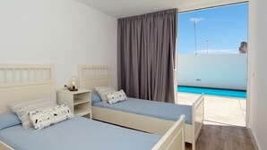 Una camera da letto con due letti, un comodino e una finestra vista mare.