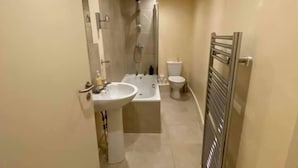 Un baño estrecho con lavamanos, inodoro y ducha.