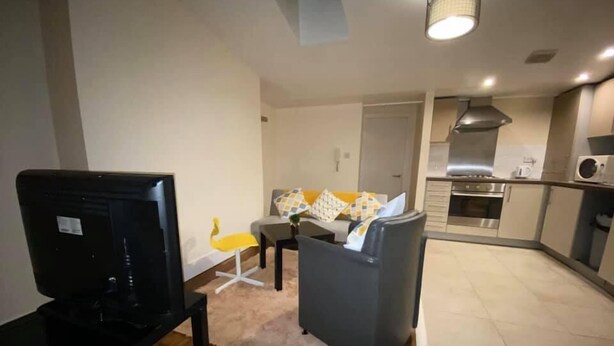 Una sala de estar moderna con un televisor de pantalla plana, un sofá y un comedor con mesa y sillas.