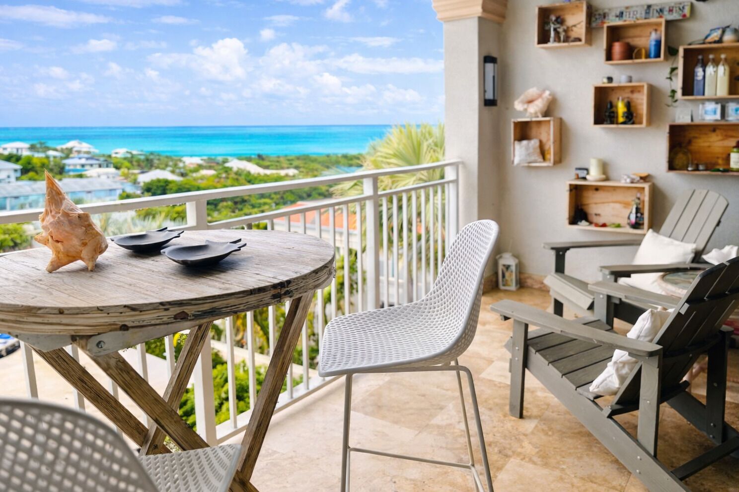 A balcony with a view of the ocean, a round wooden table with a starfish, and two chairs.