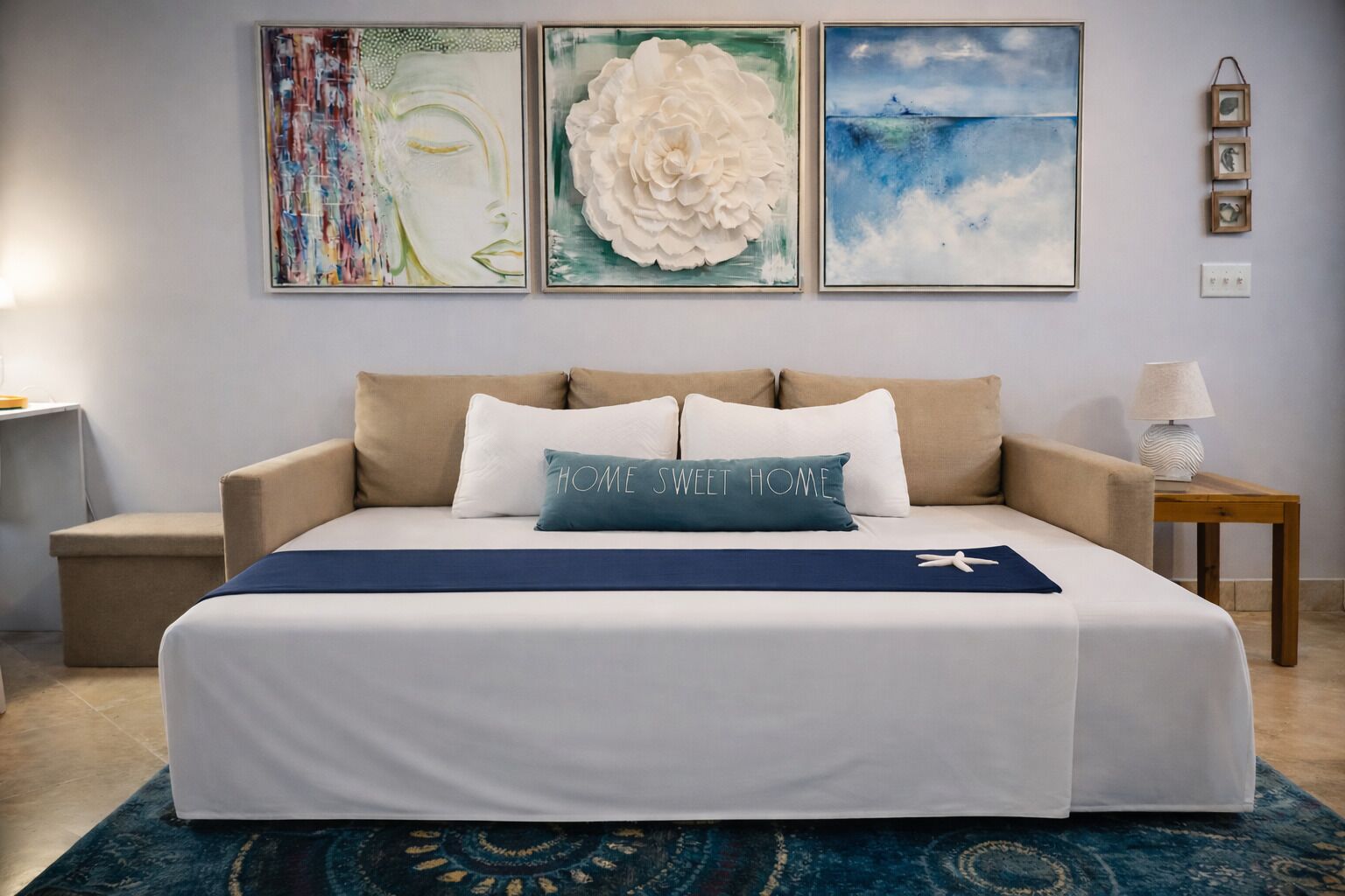 Una camera da letto con un letto, un comodino, una lampada e tre opere d'arte appese al muro.