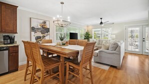 A modern kitchen with wooden cabinets, a dining table with chairs, a chandelier, and a ceiling fan. - Coastal Classic Blue Mountain Beach Condo! (Santa Rosa Beach)