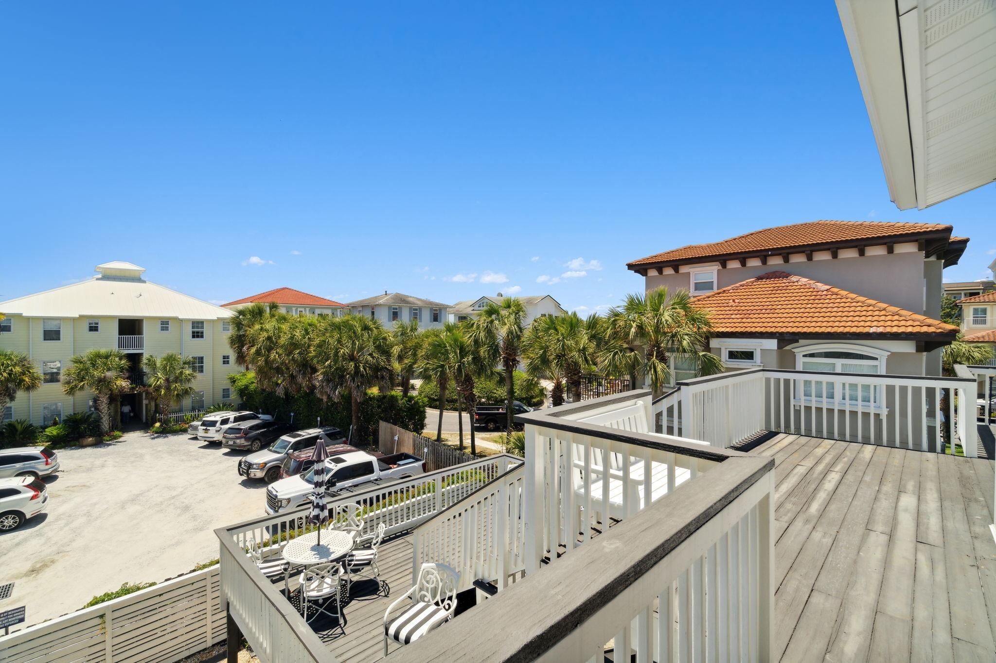 A view of a residential area with multiple houses, a parking lot, and a wooden deck.