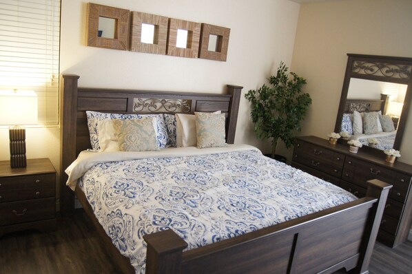 Une chambre à coucher avec un lit en bois, une table de chevet, une commode et un miroir.