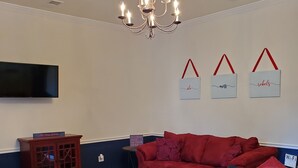 Una sala de estar con un sofá rojo, un aparador de madera y una araña.