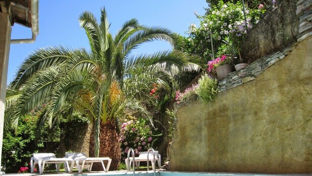Une piscine avec des chaises longues et un mur en pierre.