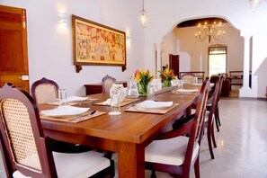 Ein Esszimmer mit einem langen Holztisch, gedeckt für sechs Personen, umgeben von gepolsterten Stühlen.