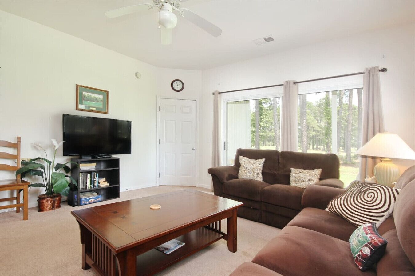 A living room with a television, bookshelf, two sofas, a coffee table, and a window with curtains.