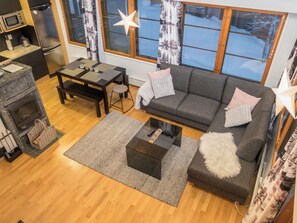 Ein gemütliches Wohnzimmer mit Kamin, einer Couch, einem Couchtisch und einem Essbereich mit Tisch und Stühlen.