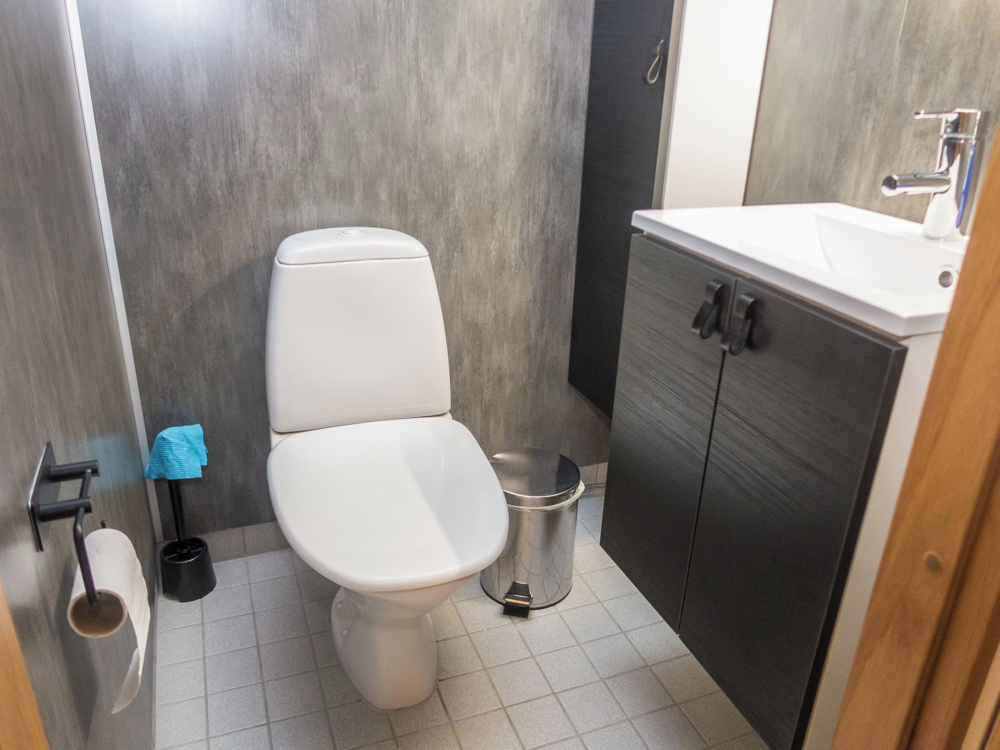 Un baño con inodoro, lavabo y cubo de basura.