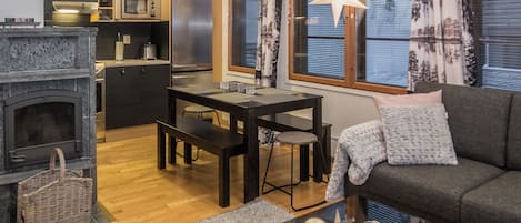 Ein gemütlicher Wohnraum mit Kamin, Essbereich, Sofa und einer Küche mit modernen Geräten.