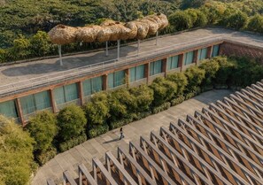 A building with a long corridor, a large woven structure on the roof, and a person walking.