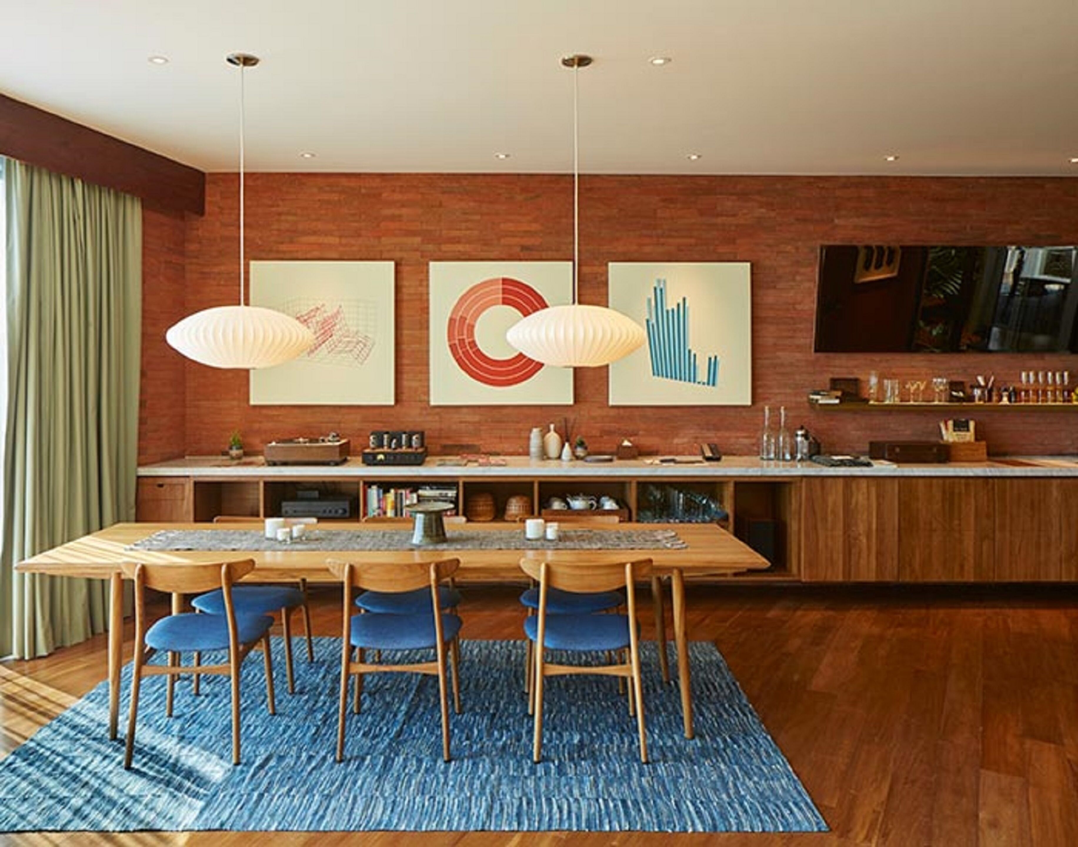 Una cocina moderna con una isla de madera, luces colgantes y una obra de arte en la pared.