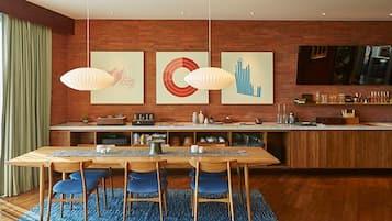 A modern kitchen with a wooden island, pendant lights, and artwork on the wall.