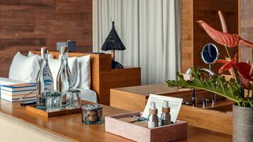 Una habitación de hotel con una cama de madera, una mesita de noche de madera con un neceser, un pequeño espejo y una planta en maceta.