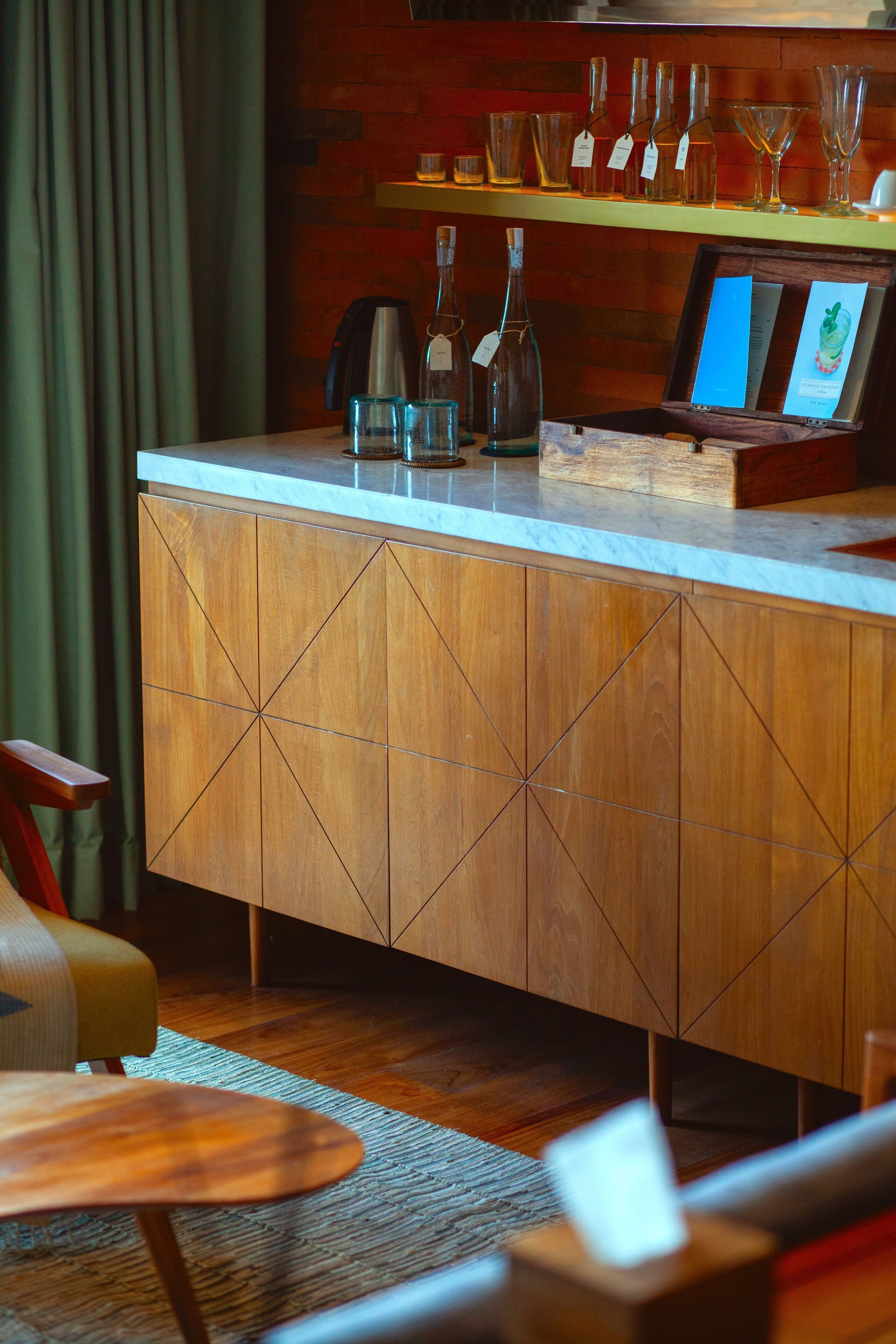 A wooden bar area with a countertop, glasses, and a framed menu.