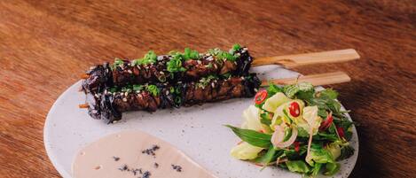 A plate with a dish and a side salad on a wooden table.