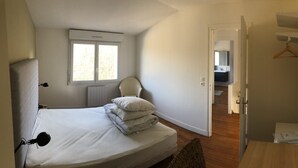 A bedroom with a bed, a window, a chair, and a door leading to a bathroom. - Les Oyats: Nature, sea, family relaxation, recharging point (Camiers)