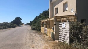 A building with a satellite dish, a sign, and a wooden fence. - Les Oyats: Nature, sea, family relaxation, recharging point (Camiers)