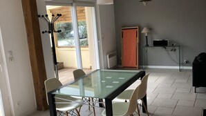 A spacious dining area with a glass-top table and four chairs, a ceiling fan, and a view of the outdoors. - Les Oyats: Nature, sea, family relaxation, recharging point (Camiers)