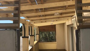 A covered outdoor area with wooden flooring and a view of greenery outside. - Les Oyats: Nature, sea, family relaxation, recharging point (Camiers)