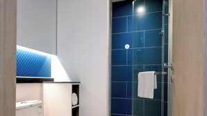 Une salle de bain moderne équipée de toilettes, d’une douche à parois de verre et d’un porte-serviettes.