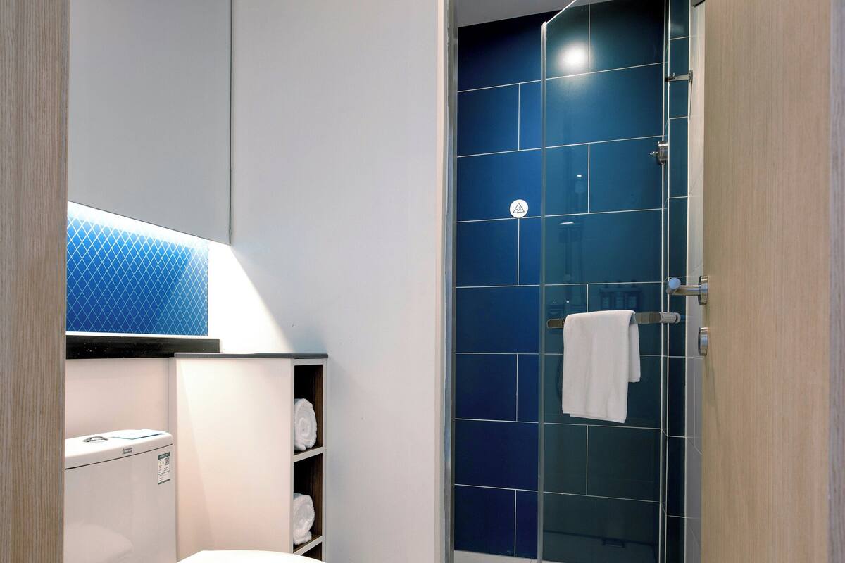 A modern bathroom with a toilet, a glass shower enclosure, and a towel rack.