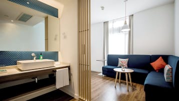 A modern bathroom with a large mirror, sink, and wooden floor.