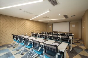 Une salle de conférence équipée d’une grande table, de chaises, d’un écran de projection et d’un mur décoré de motifs.
