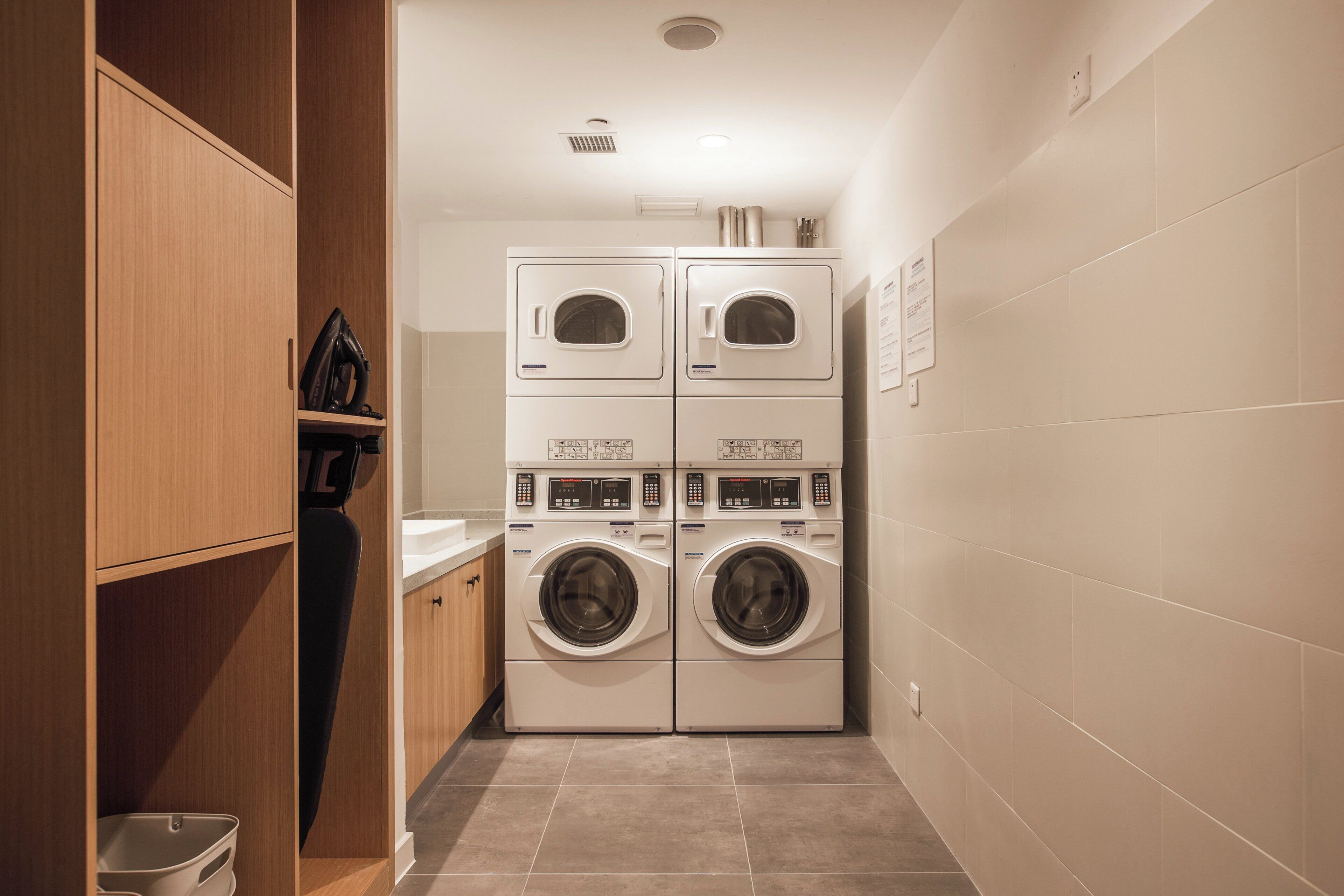 A laundry room with two stacked front-loading washing machines and a dryer.
